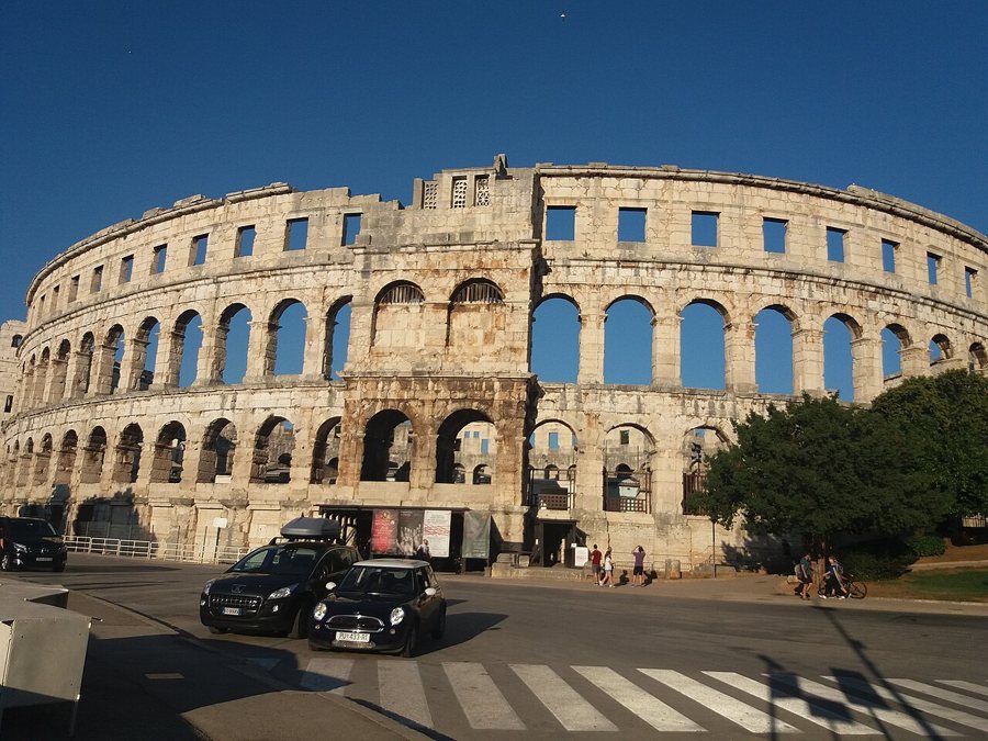 Die steinerne Außenfassade des römischen Amphitheaters von Pula mit übereinanderliegenden Bogenreihen.